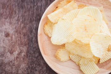 Crispy potato chips on wooden background