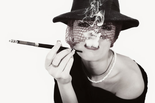 woman with cigarette in mouthpiece in hat with vei