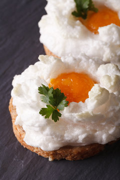 Eggs Orsini: baked whipped whites and yolk on toast. Vertical close-up

