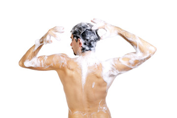 Young naked man taking a shower in foam