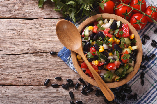 Mexican vegetable salad in a wooden bowl, close-up horizontal top view
