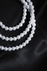 white pearl necklace on a black silk close up