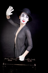 Female mime in white gloves with a suitcase