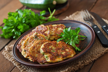 Zucchini pancakes with parsley on a wooden table.
