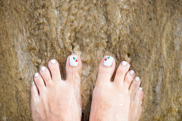 Female Foot with Beautiful Pedicure on the sand. Moving Sea Wate