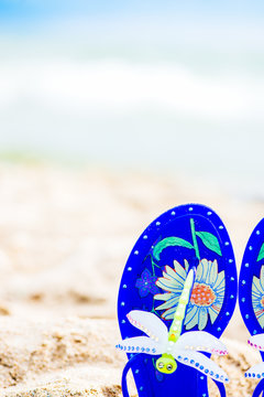 Blue Jelly Sandals With Dragonfly Laying On The Sand. Sea On The