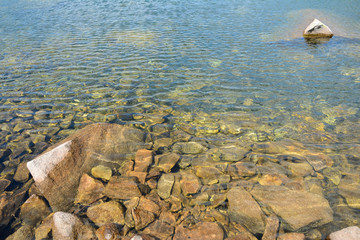 Clear water and stones in lake in mountains.