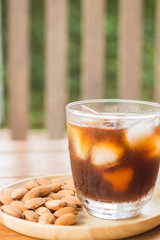 Glass of black iced coffee with almond grain
