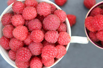 A cup of raspberry standing on grey background. Harvest of raspberry