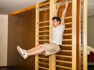 Young man hanging from gym equipment