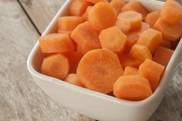 carrots cut in bowl close up on wooden background