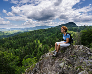 Naklejka na ściany i meble Woman sitting on a mountain peak