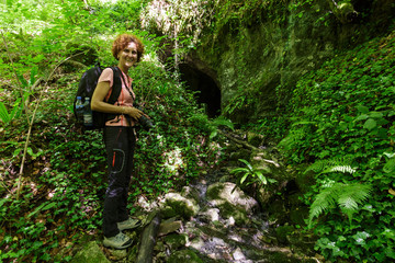 Naklejka na ściany i meble Woman standing near a cave