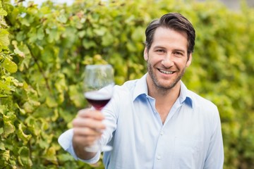 Young happy man smiling at camera and holding a glass of wine