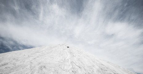 Grey Mountain relief against the blue sky with grey clouds volume