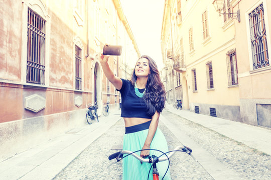 pretty young girl with a bike takes a selfie around town