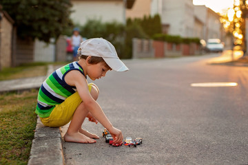 Cute little boy, playing with little toy cars on the street on s