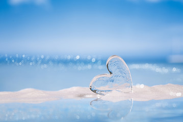clear glass heart on white sand beach  glitter glass  and reflec