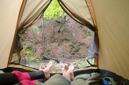 Young couples legs in a tent together on the mountains backgroun