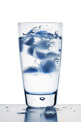 Blue tinted ice cubes in glass of water