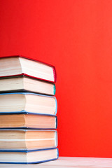 old hardback books, diary, fanned pages on red background
