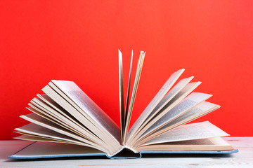 old hardback books, diary, fanned pages on red background