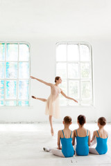 Obraz premium Three little ballerinas dancing with personal ballet teacher in