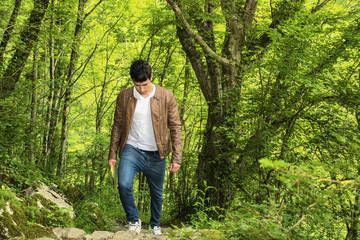 Naklejka na ściany i meble Young man hiking in lush green mountain scenery