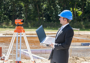 junger bauingenieur mit laptop schaut in die ferne