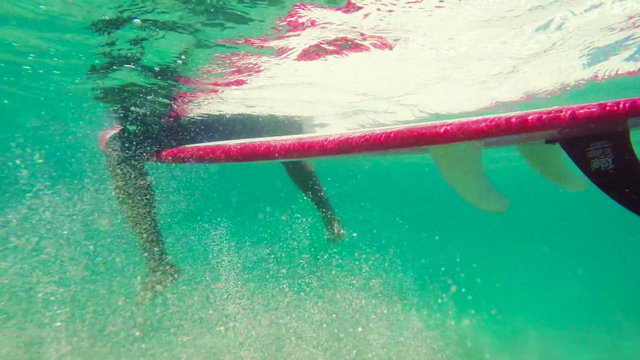 Underwater Shot of Surfer Sitting on a Longboard Dangling His Feet in the Blue Ocean