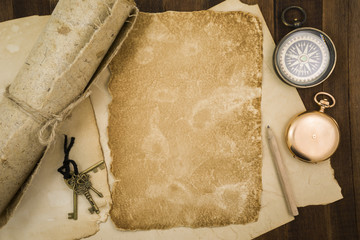 Old paper, compass, pocket watch on wooden background