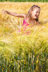 Little girl having fin in the wheat field