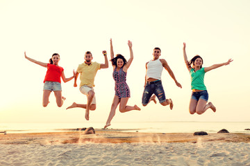 Fototapeta na wymiar smiling friends dancing and jumping on beach