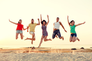Obraz premium smiling friends dancing and jumping on beach