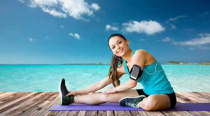 Fototapeta na wymiar smiling woman stretching leg on mat over sea