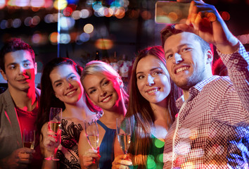 friends taking selfie by smartphone in night club