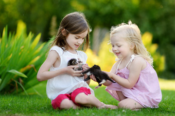 Two cute sisters playing with little kittens © MNStudio