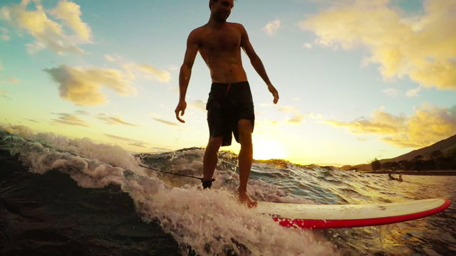 Attractive Young Hawaiian Surfer Rides a Longboard On a Blue Ocean Wave Through a Golden Sunset in Slow Motion