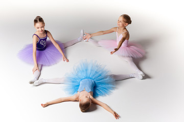 Three little ballet girls sitting in tutu and posing together