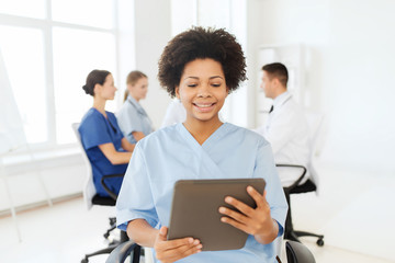 happy nurse with tablet pc over team at hospital