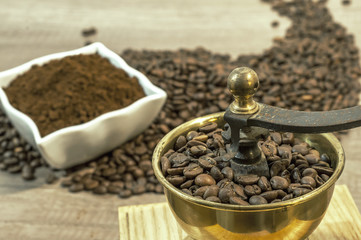 Coffee grinder with coffee beans and ground coffee in bowl on wo