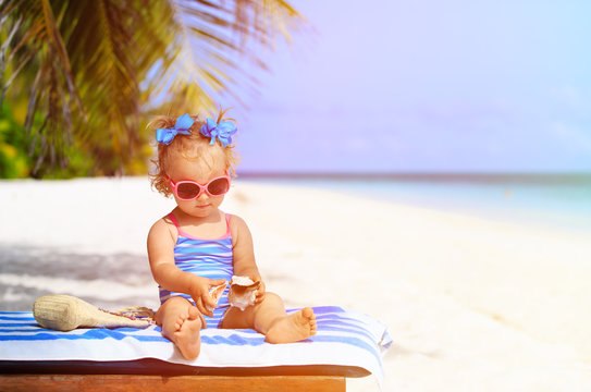 cute little girl with seashells on summer beach