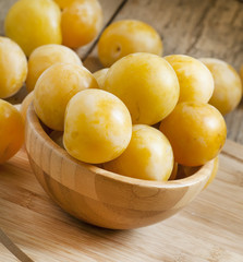 Ripe juicy yellow plums in a wooden bowl, selective focus