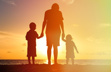 Fototapeta na wymiar father and two kids walking at sunset