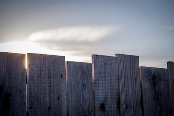 Die Sonne versteckt sich hinter einem Zaun