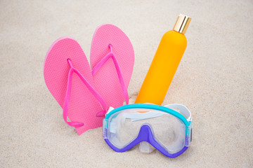 Fototapeta na wymiar summer concept - diving mask, slippers and suntan lotion bottle
