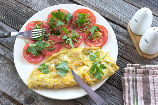 Omelette with vegetables on wooden background