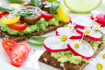 Vegan sandwiches with smashed avocado, tomatoes and radish. Top