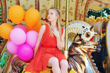 Obraz na płótnie Canvas Blonde teenager having fun in the park riding a carousel