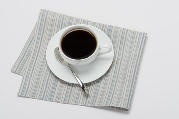 Black Coffee In White Cup On Folded Natural Linen Napkin. White